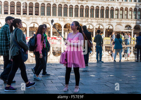 Woman in pink dress outfit takes a selfie in Saint Marks Square, Venice, Italy Stock Photo