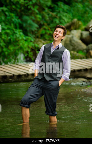 Elegant young man enjoying the nature with his feet inside a lake Stock Photo