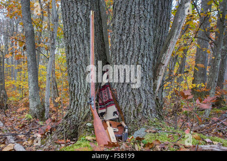 A hand-made flintlock rifle and accessories adorn a rotting stump