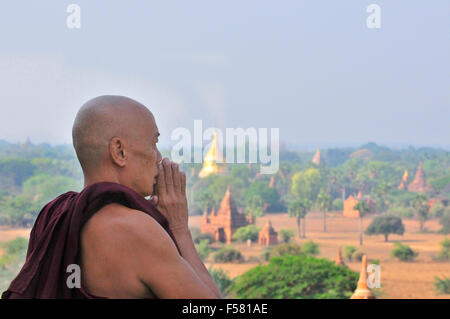 Buddhist Monk praying on top of the Shwesandaw Pagoda in Bagan, Myanmar formerly known as Burma Stock Photo