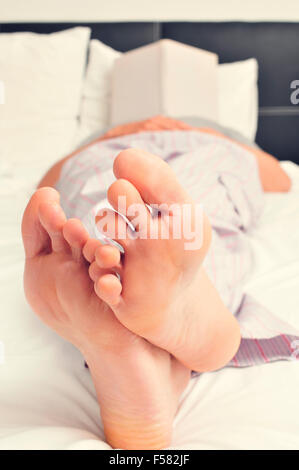 a young caucasian man in pajamas fell asleep while reading a book in bed Stock Photo