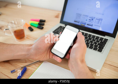 man using smartphone with white screen near laptop in home interior Stock Photo