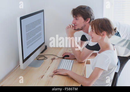 young couple looking at computer at home Stock Photo