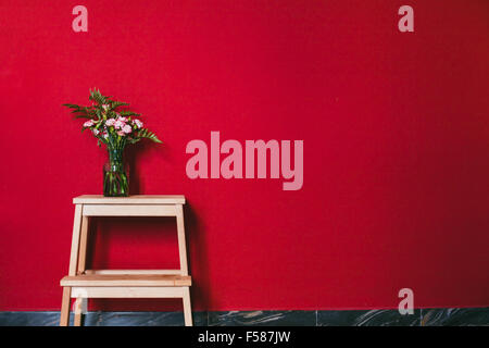 simple design of interior, flowers in vase on red wall background Stock Photo