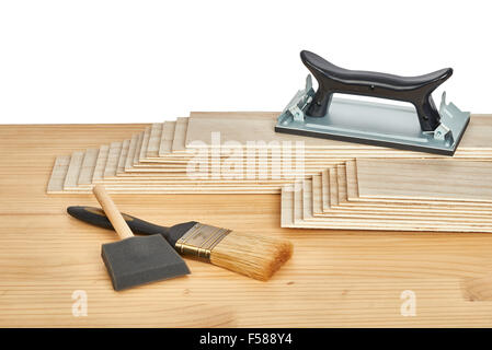 carpentry and painting tools, such as sandpaper holder, stack of veneers and paint brushes,  on a worktable Stock Photo