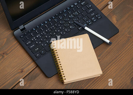 laptop computer and memo note with ballpoint pen on a wooden desk Stock Photo