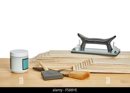 carpentry and painting tools, such as sandpaper holder, stack of veneers and paint brushes,  on a worktable Stock Photo