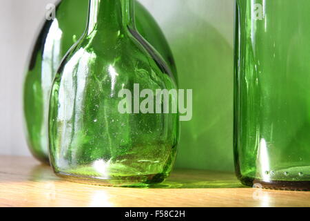Three old green glass bottles over wooden surface. Closeup, daylight Stock Photo