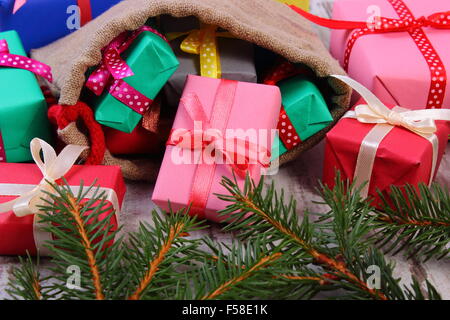 Wrapped colorful gifts for Christmas, birthday or other celebration in jute bag and green spruce branches Stock Photo