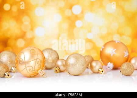 Golden Christmas baubles in front of defocused golden lights. Stock Photo
