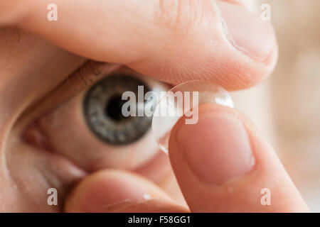 A man is inserting a contact lens into his left eye. Stock Photo