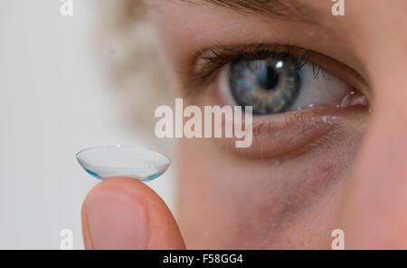 A young man is balancing a contact lens on is index finger. Stock Photo