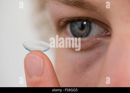 A young man is balancing a contact lens on is index finger. Stock Photo