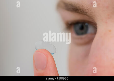 A young man is balancing a contact lens on is index finger. Stock Photo