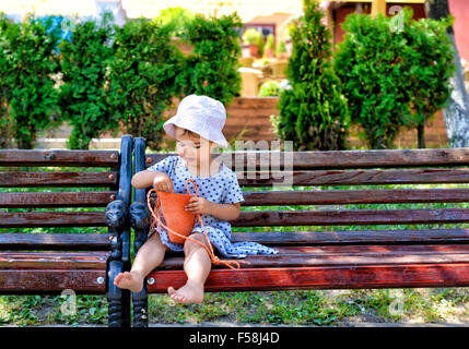 trendy little girl sitting on a wood bench with her handbag Stock Photo