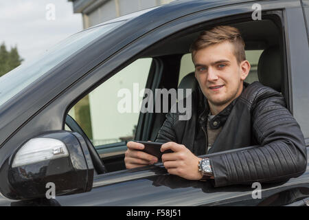 Happy young man in a car with a cell phone Stock Photo