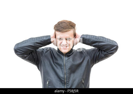 Young man pressing his hands against his ears, in an attempt to shut out a painful noise. Isolated, white background. Medium shot. Stock Photo
