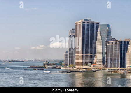 Skyline manhattan seen from Brooklyn Bridge with view on Statue of Liberty in background Stock Photo