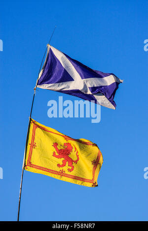 The two flags of Scotland - St Andrews' cross and the lion rampant - blow in the wind against a blue sky Stock Photo