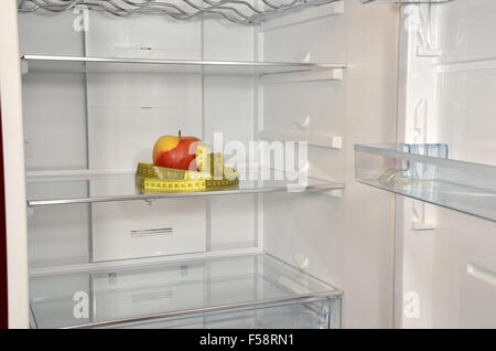 Red apple and yellow measure tape in empty refrigerator Stock Photo