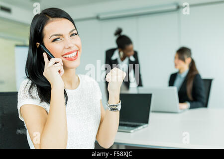 Beautiful businesswomen in an office working on a laptop and calling potential partners Stock Photo