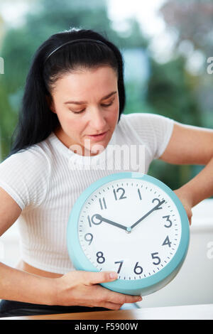 Woman adjusting the time on a clock Stock Photo