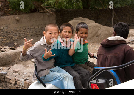 India, Himachal Pradesh, Spiti Valley, Khurik village, three young boys riding on tractor making hand gestures Stock Photo