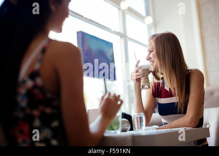 Women talking in restaurant while enjoying their beverages Stock Photo