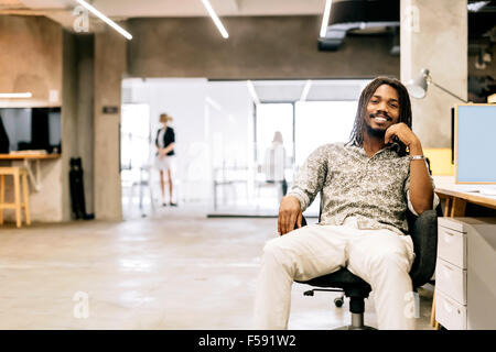 Handsome graphics designer sitting at a desk in an office Stock Photo