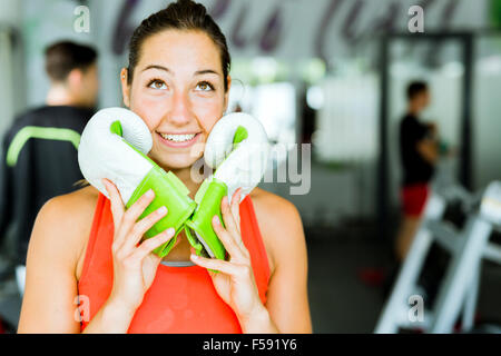 Young beautiful woman smiling and posing with boxing gloves in a gym Stock Photo