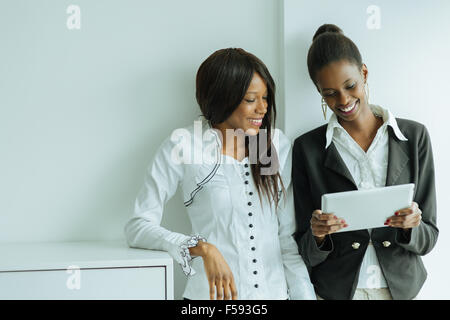 Two colleagues talking while standing about the contents on a tablet pc in a well lit office close to the window Stock Photo