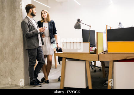 Colleagues using phone in an office and talking Stock Photo