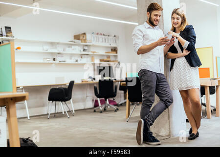 Creative smart colleagues in office using phones and smiling Stock Photo