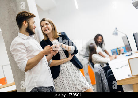 Creative smart colleagues in office using phones and smiling Stock Photo