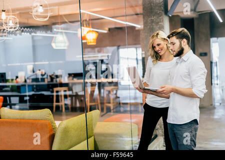 Cowerkers looking at notebook in a modern office Stock Photo
