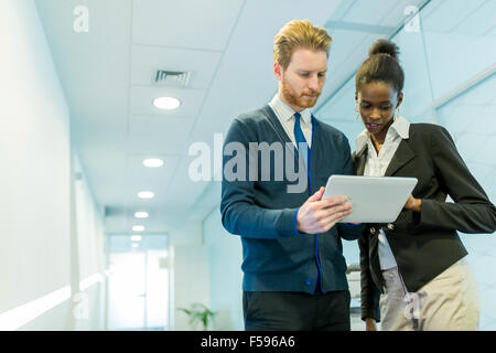 Business partners and colleagues discussing ideas displayed on a tablet on an office corridor Stock Photo