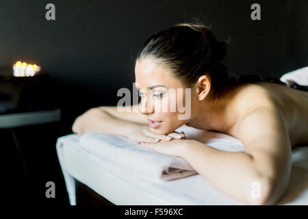 Portrait of a young and beautiful woman  relaxing with eyes open on a massage table in a dark room with candlelight Stock Photo