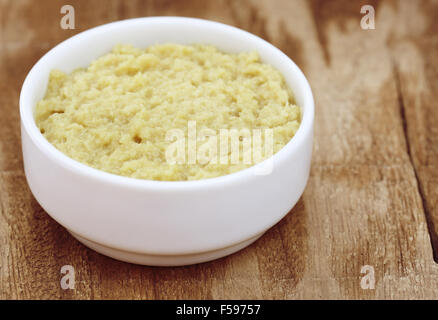 Crushed ginger in a white bowl on wooden surface Stock Photo