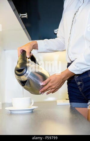 Closeup of hot water being poured out of the kettle in a modern kitchen Stock Photo
