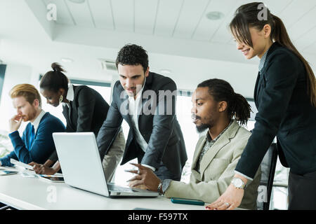 Colleagues brainstorming at a desk in on office with phones, tablets and notebooks Stock Photo