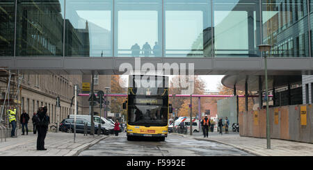 Berlin-Mitte, Germany. 30th Oct, 2015. A double-decker bus from the Berliner BVG drives under the new bridge of the at the Charité in Berlin-Mitte, Germany, 30 October 2015. As part of the construction work, the connecting bridge between the patient residence and the campus has been renewed and the existing bridge structure replaced by a transparent structure made of steel and glass. The old bridge was too low for such busses to pass under. Photo: BERND VON JUTRCZENKA/dpa/Alamy Live News Stock Photo