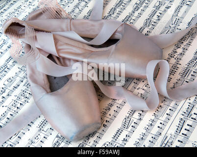 Pair of old used ballet slippers on a music sheet Stock Photo