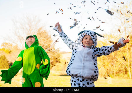 Two boys in costume catching and throwing leaves Stock Photo