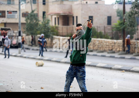 Bethlehem, Mideast. 30th October, 2015. A female Palestinian demonstrator is seen using a slingshot against Israeli soldiers (not seen) during clashes in the West Bank city of Bethlehem. Following another Day of Rage across the Occupied West Bank and Gaza, an 8-month-old Palestinian infant, Ramadan Mohammad Faisal Thawabta, died from tear gas inhalation in the West Bank village of Beit Fajjar, south of Bethlehem. The infant's death came during clashes between Palestinian youth and Israeli soldiers in the village. Credit:  PACIFIC PRESS/Alamy Live News Stock Photo