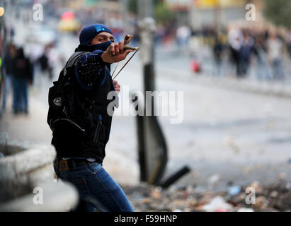 Bethlehem, Mideast. 30th October, 2015. A female Palestinian demonstrator is seen using a slingshot against Israeli soldiers (not seen) during clashes in the West Bank city of Bethlehem. Following another Day of Rage across the Occupied West Bank and Gaza, an 8-month-old Palestinian infant, Ramadan Mohammad Faisal Thawabta, died from tear gas inhalation in the West Bank village of Beit Fajjar, south of Bethlehem. The infant's death came during clashes between Palestinian youth and Israeli soldiers in the village. Credit:  PACIFIC PRESS/Alamy Live News Stock Photo