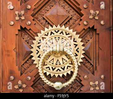 Luxury Golden doorknocker over carved wooden door Stock Photo