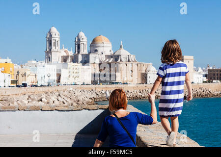 Tourists mother and daughter with blue striped t shirt on the promenade with the Cathedral of Cadiz, Andalusia, Spain Stock Photo