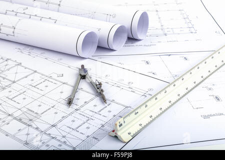 Compasses and Architect scale ruler placed on the desk, filled with building plans. In order to work in a building Stock Photo