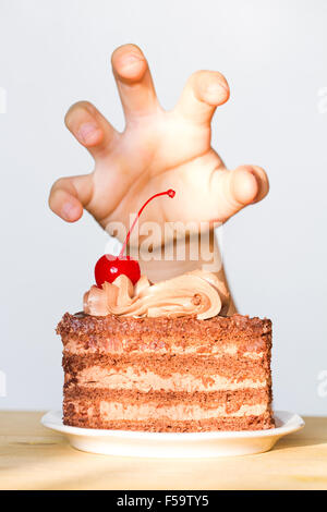 Greed for sweets concept with hand and chocolate cake concept Stock Photo