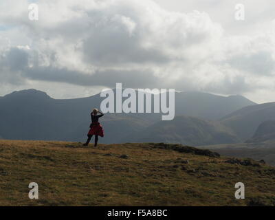 Walker surveys the sunlit view from summit of Eye Spy on Newlands Horseshoe above Borrowdale in Cumbria UK Lake District Stock Photo